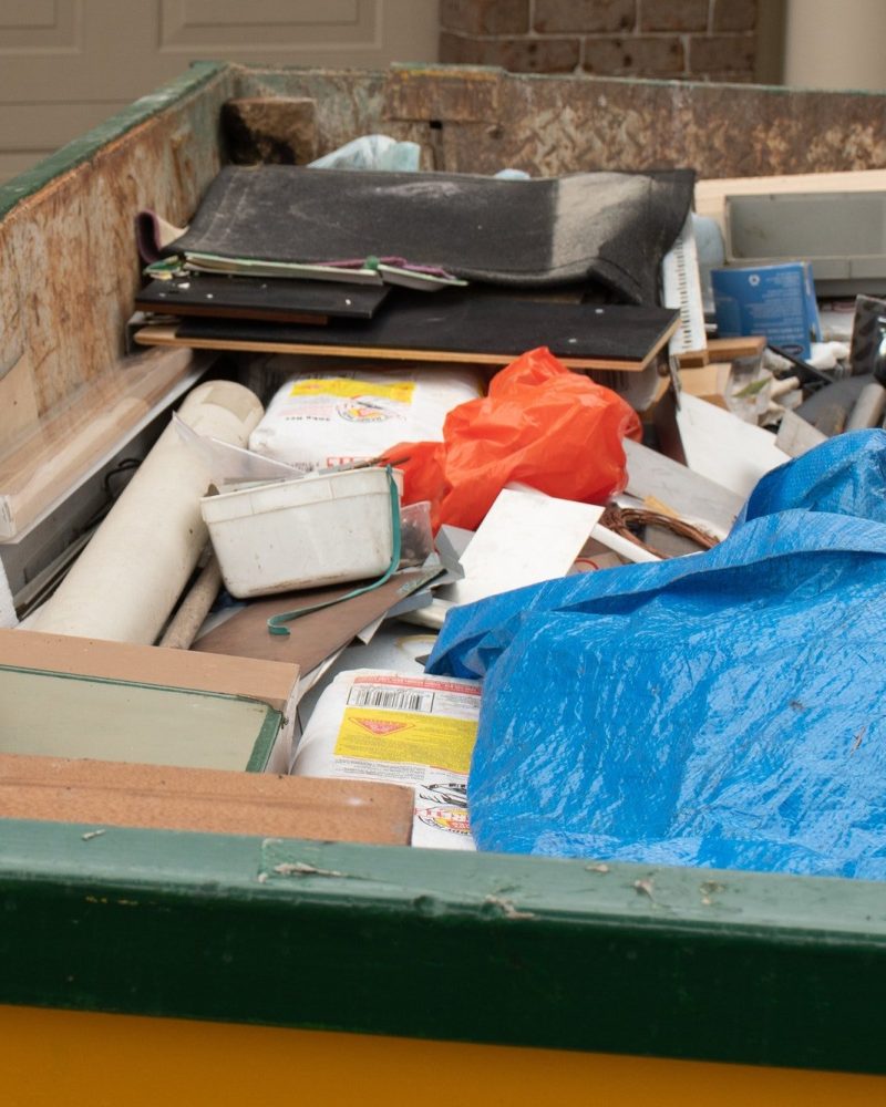 Skip bin full of household waste rubbish on the front yard. House clean up