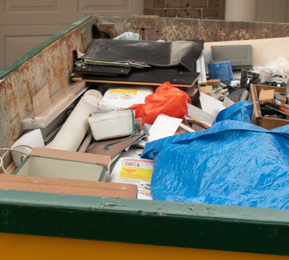 Skip bin full of household waste rubbish on the front yard. House clean up